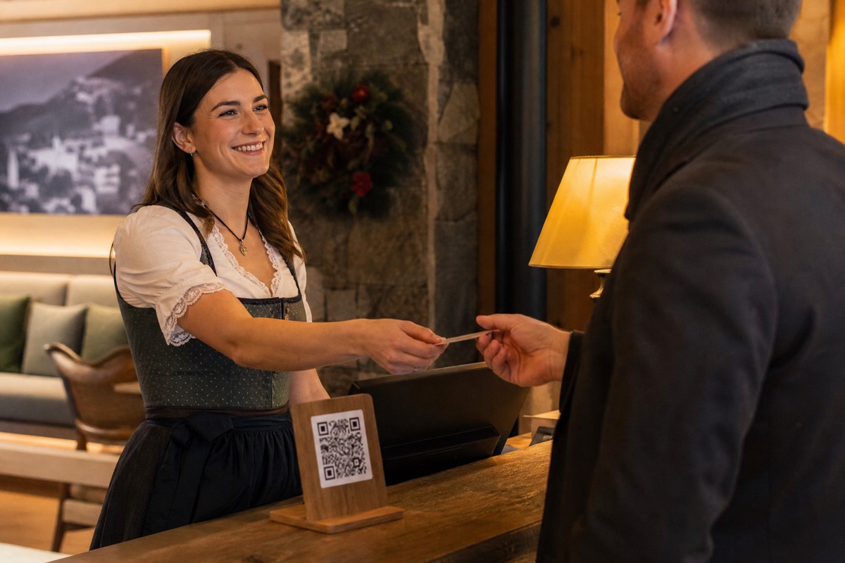 Alpine Hotel-Rezeption am Abend mit QR-Aufsteller auf dem Tresen